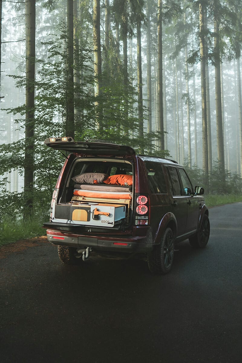 Campingbox von EGOÉ Camper 200 Kochmodul / Heckküche mit zusammengeklappter Liegefläche, ausgezogenem Küchenmodul in einem Land Rover Discovery