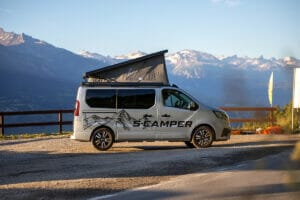 S-Camper Renault Campervan mit Markise und Aufstelldach im Hintergrund Berge